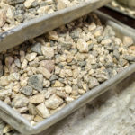 Crushed stone, fine crushed stone fraction. The laboratory sample lies in a rectangular aluminum tray.