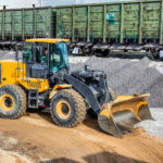 A wheel loader picks up gravel into a bucket. Transportation of inert materials for concrete production.
